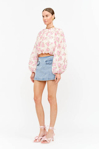 Model wearing a soft pink floral long sleeve blouse with a billowy silhouette, gathered neckline, and elasticized cuffs