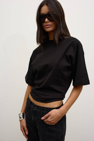 Person wearing a black crop top and sunglasses against a plain background