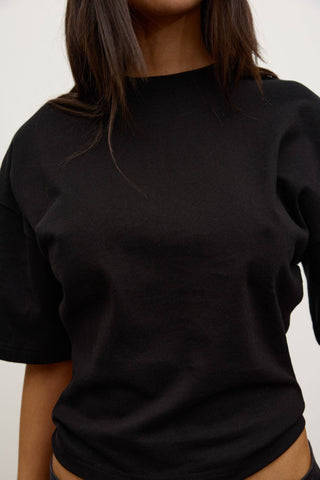 Person wearing a plain black t-shirt against a white background