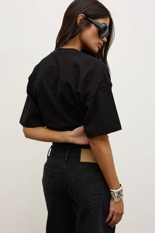 Person wearing a black oversized t-shirt and black pants against a white background