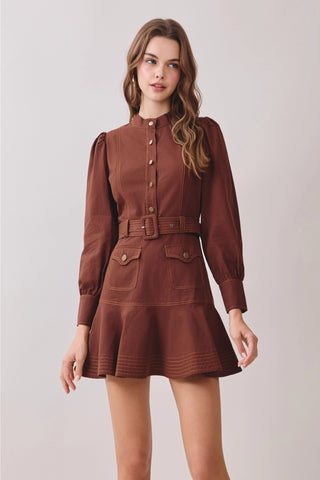 Shop the chocolate brown belted mock neck mini dress with contrast stitching, puff sleeves, flap pockets, and flounced hem. A chic cinched silhouette for fall and beyond.
