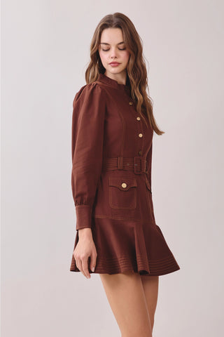 Shop the chocolate brown belted mock neck mini dress with contrast stitching, puff sleeves, flap pockets, and flounced hem. A chic cinched silhouette for fall and beyond.