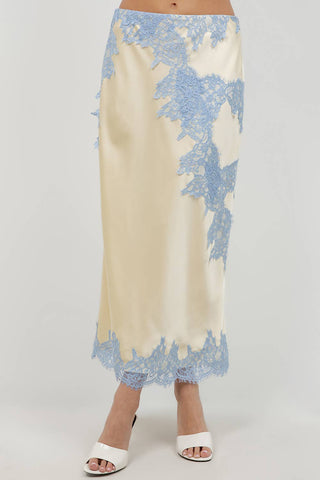 Long beige skirt with blue floral lace trim worn by a person on a white background