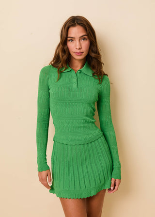 Woman wearing a green knitted outfit against a beige background