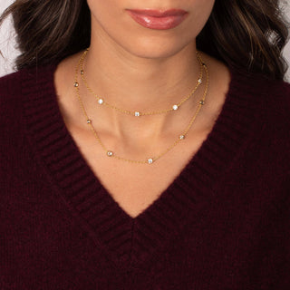 Close-up of a person wearing a gold necklace with a maroon sweater.