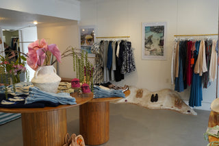 Interior of a store with clothing racks, plants, and decorative items.