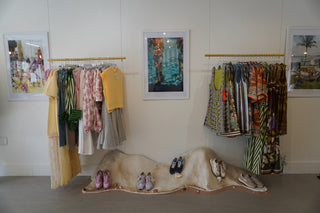 Clothing rack with various garments against a wall with framed pictures.