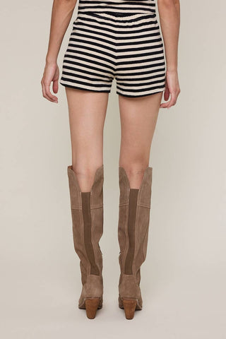 Person wearing striped shorts and brown knee-high boots on a plain background
