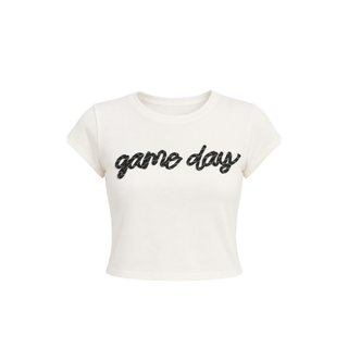 An off-white cropped short-sleeve t-shirt with 'game day' written across the chest in black cursive text, shown against a plain white background.