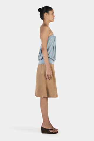Woman wearing a strapless top and beige skirt on a white background