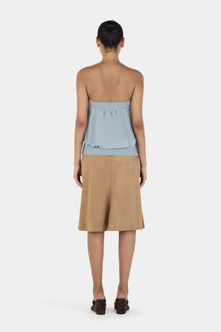 Woman wearing a strapless top and beige skirt on a white background