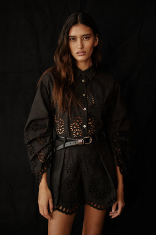 Woman wearing a black outfit with intricate designs on a dark background