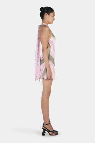Woman wearing a patterned dress with a pink scarf on a white background