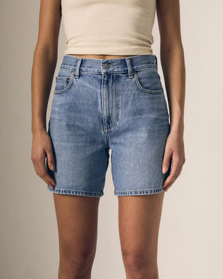 Person wearing blue denim shorts on a plain background
