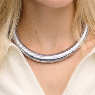Silver necklace worn by a person with a neutral background