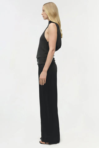 Woman wearing a black sleeveless top and long black pants on a white background