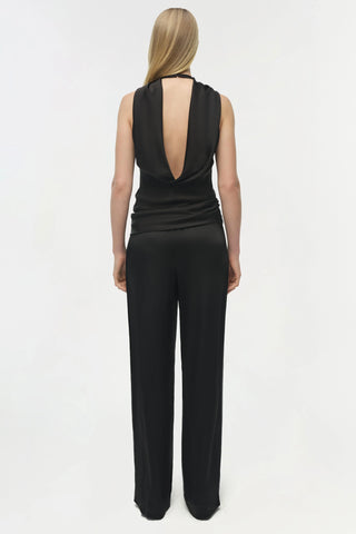 Person wearing a black sleeveless top and wide-leg pants on a white background
