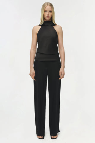 Woman wearing a black sleeveless top and pants on a white background