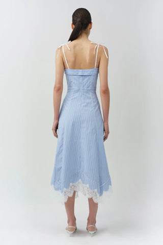 Woman wearing a light blue dress with lace details on a white background