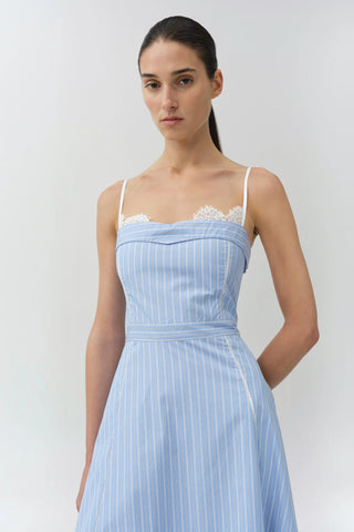 Woman wearing a light blue dress with lace straps against a white background