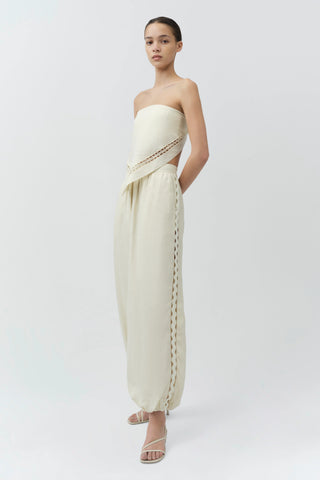 Woman wearing a strapless, off-white dress with lace details on a white background
