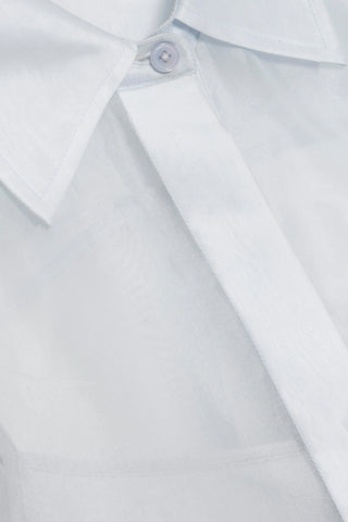 Close-up of a white shirt with a collar and button on a light gray background