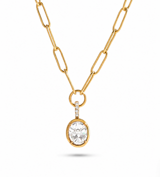 A gold paperclip chain necklace with a round bezel-set clear gemstone pendant, shown on a clean white background.