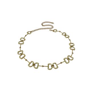 A gold-toned horsebit chain necklace arranged in a circle on a plain white background.