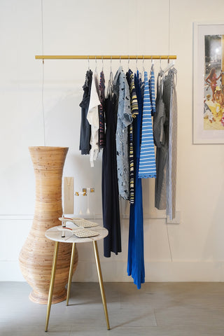 Clothing rack with folded clothes against a white wall