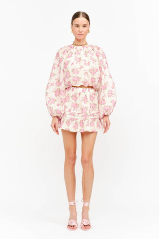 Model wearing a soft pink floral long sleeve blouse with a billowy silhouette, gathered neckline, and elasticized cuffS