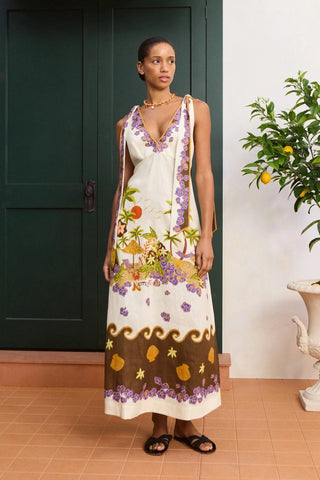 Woman wearing a floral dress standing in a room with a green door and plant.