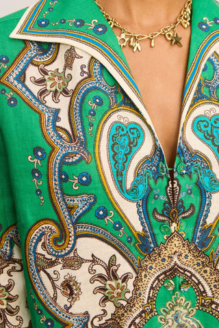 Close-up of a green patterned garment with gold accents and a necklace.