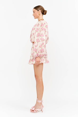 Model wearing a soft pink floral long sleeve blouse with a billowy silhouette, gathered neckline, and elasticized cuffs