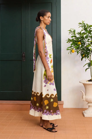 Woman in a floral dress standing next to a plant indoors