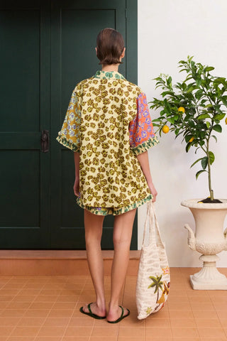 Woman in a floral outfit holding a matching bag in a home setting.