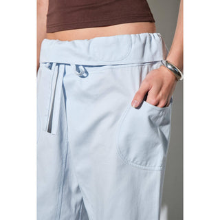 Light blue pants with a brown top on a neutral background
