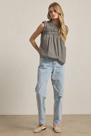 Woman wearing a checkered top and light blue jeans against a plain background