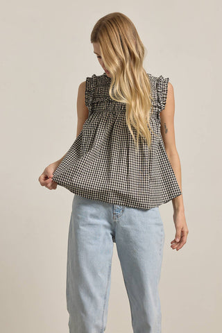 Woman wearing a checkered dress and light blue jeans on a beige background