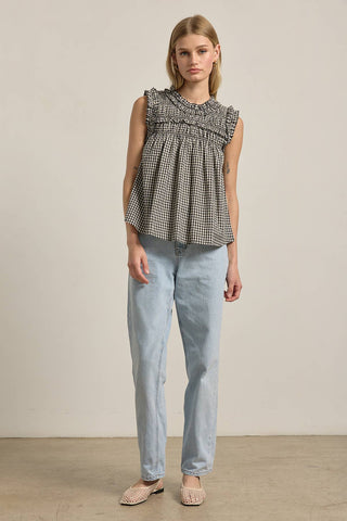 Woman wearing a checkered top and light blue jeans against a plain background