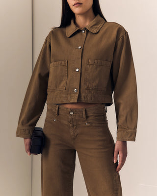 Person wearing a brown jacket and pants against a neutral background