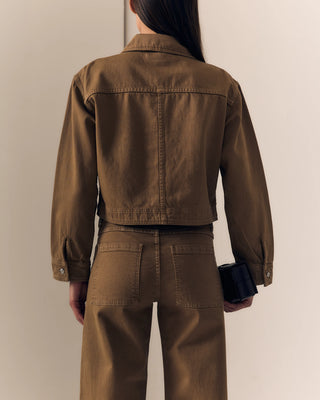 Person wearing a brown jacket and pants against a plain background