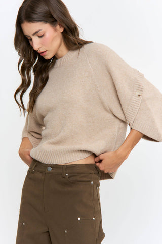 Woman wearing a beige sweater and brown pants on a white background