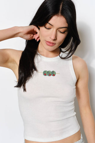 Woman wearing a white sleeveless top with a small graphic design on a plain background
