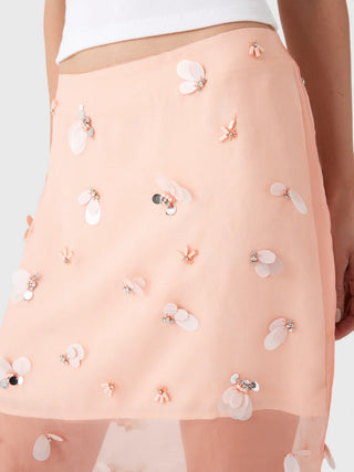 Light pink skirt with floral embellishments on a neutral background