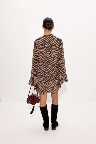 Person wearing a zebra print dress with black boots on a white background