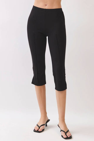 Black cropped capri pants worn by a model, paired with black strappy sandals, shown against a plain light gray studio background.