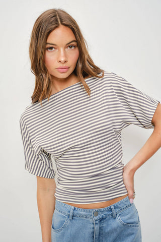 Woman wearing a striped shirt and jeans on a plain background