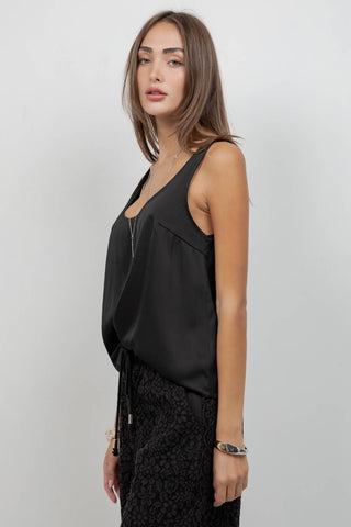 Woman wearing a black sleeveless top and black lace skirt against a white background