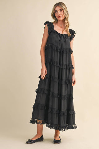 Woman wearing a black ruffled dress on a beige background