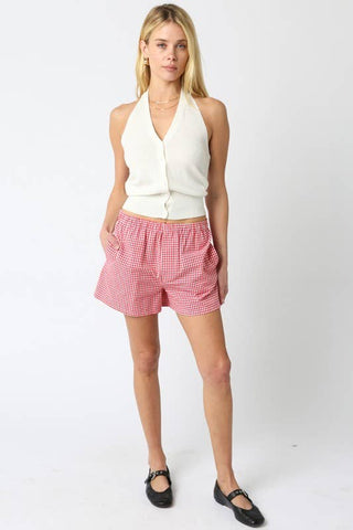 Woman wearing a white halter top and red checkered shorts on a white background